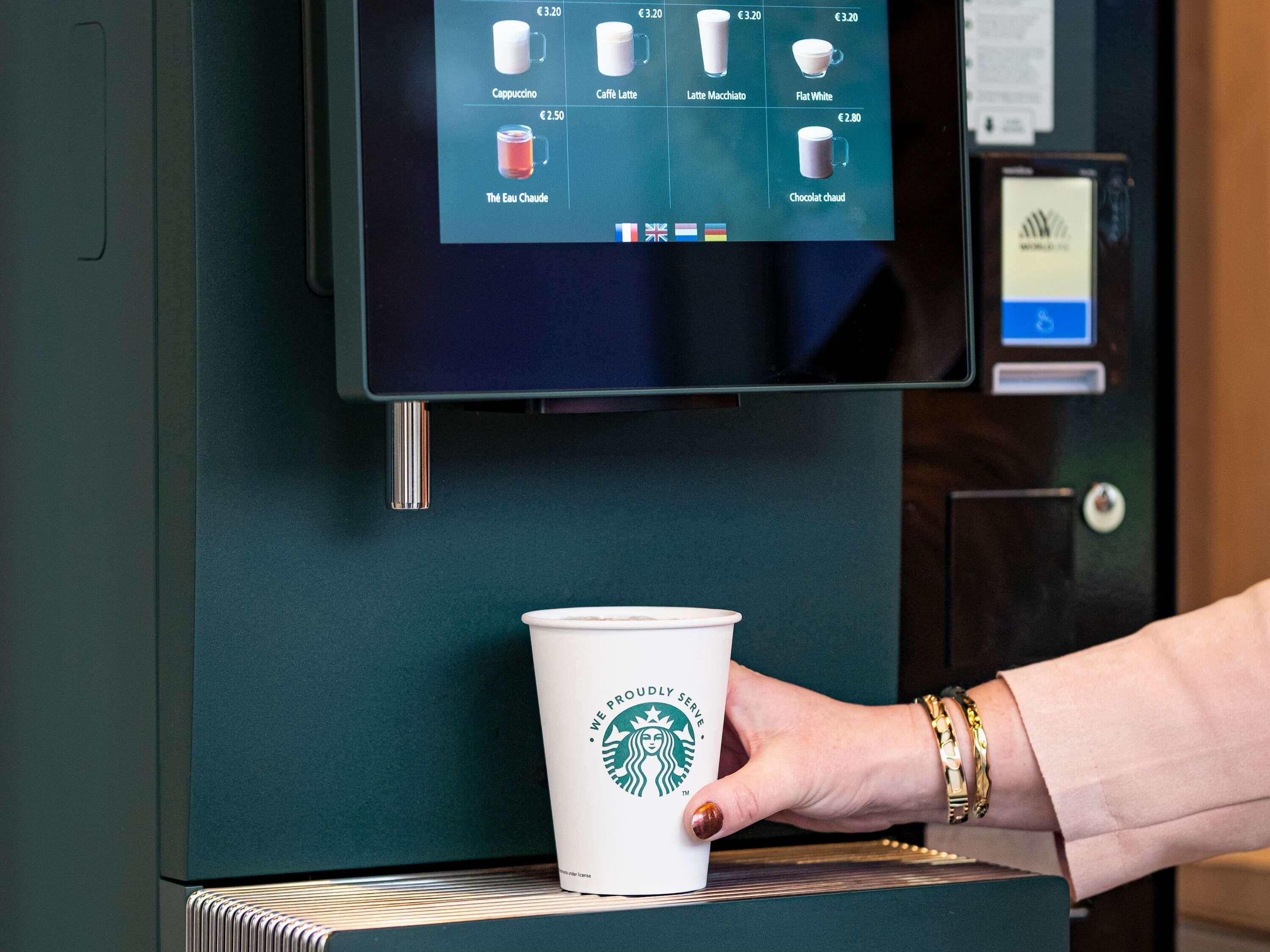 A Starbucks coffee machine with a digital menu displaying various coffee options and prices.