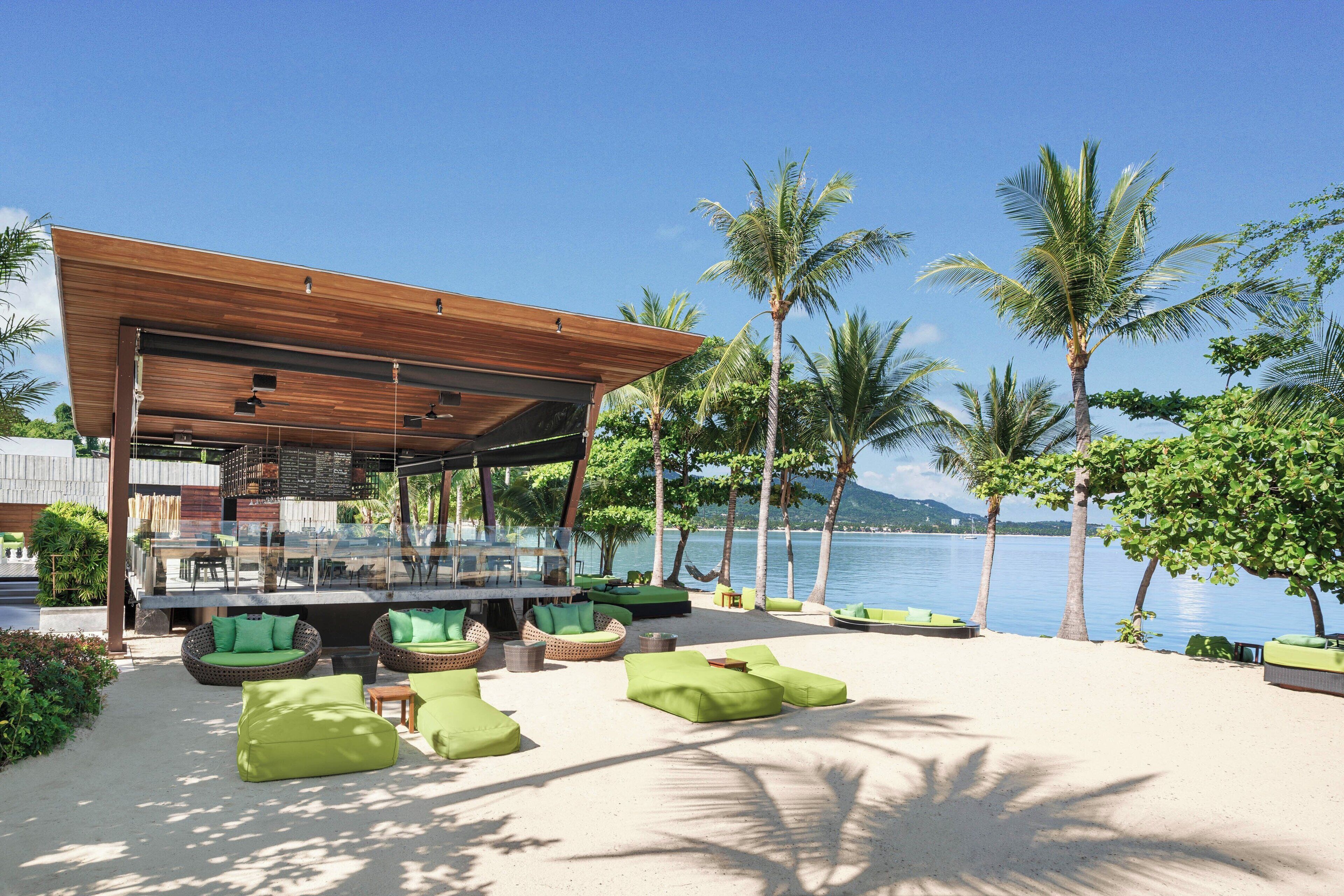Eine Strandlounge mit Sitzgelegenheiten im Freien und einem überdachten Bereich mit Blick aufs Meer.