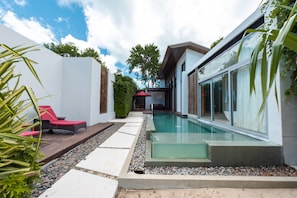 Relax by the pool surrounded by a pebble-lined walkway and lounge chairs on a deck.
