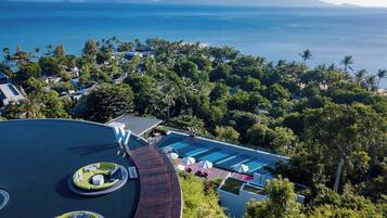 Un complexe hôtelier doté d’une grande piscine, d’une végétation luxuriante et offrant une vue sur l’océan.