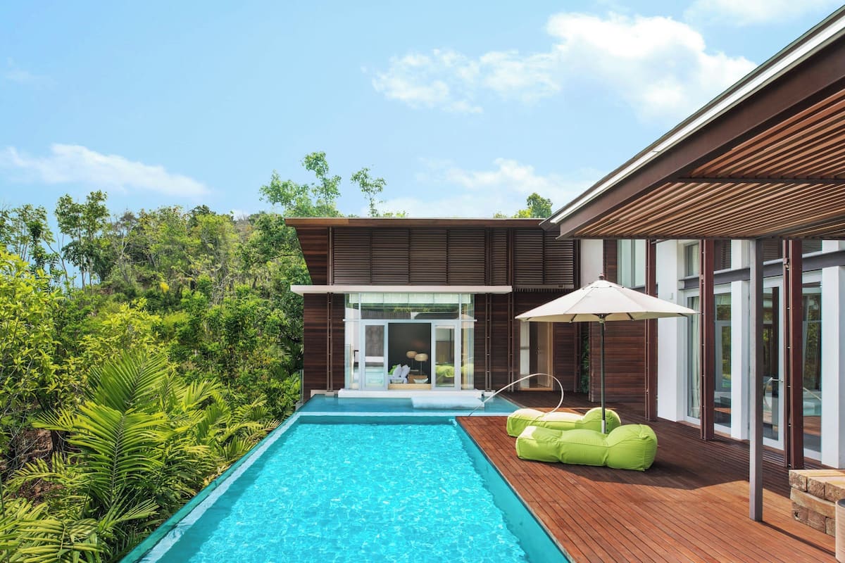 A modern house with a swimming pool, wooden deck, and green outdoor seating.
