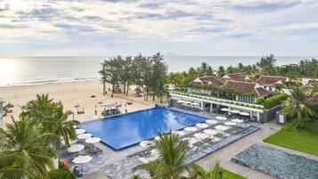 Una piscina al aire libre, sombrillas, sillones reclinables de piscina