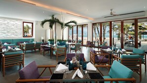 Un restaurante con mesas y sillas, amplias ventanas y vista al mar.