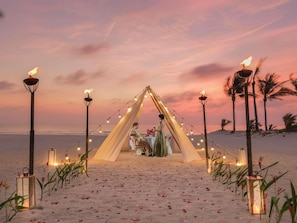 A beach setting with a tented dining area, string lights, and lanterns. - Pullman Danang Beach Resort (Da Nang)