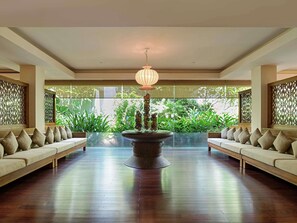 A spacious room with a central fountain, two sofas facing each other, and a view of lush greenery outside.