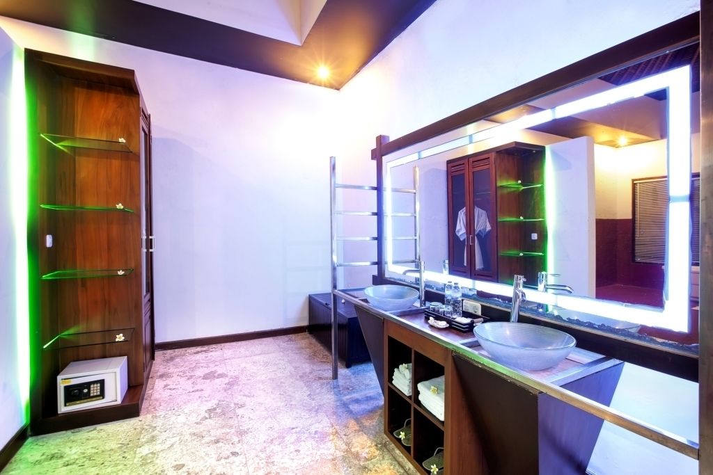 A modern bathroom with a large mirror, two sinks, and a wooden vanity.