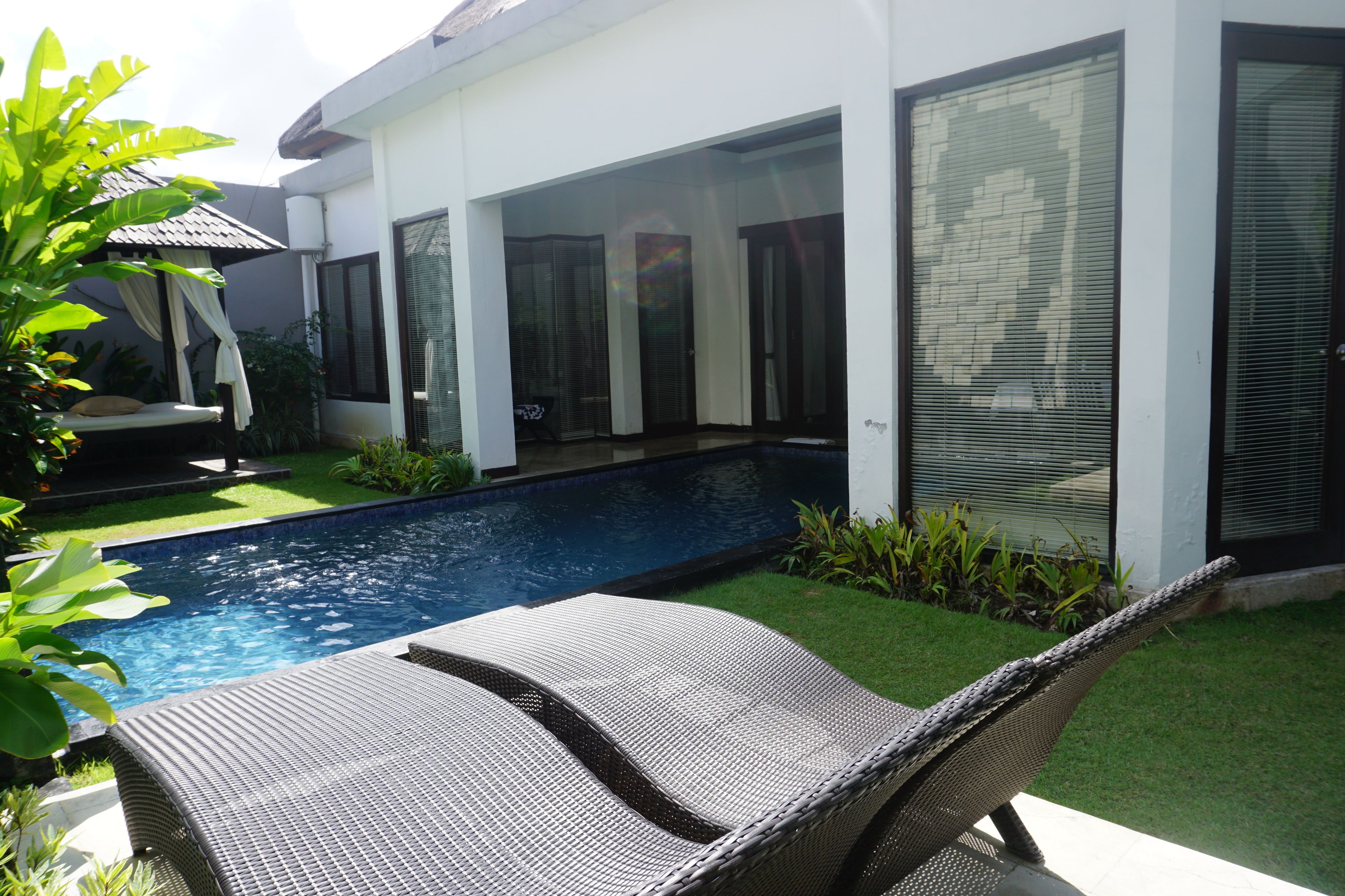 A modern house with a swimming pool, outdoor seating, and a well-maintained lawn.