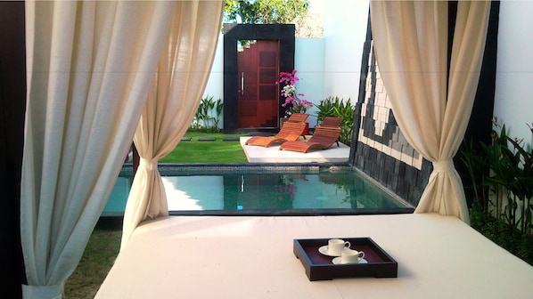 A private pool area with a lounge chair and a tray of white cups.