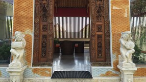 Una entrada ornamentada con intrincados grabados, una reja de metal y dos estatuas a cada lado.