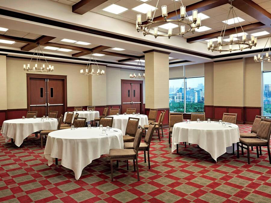 Un salón de conferencias con mesas redondas, sillas y candelabros.