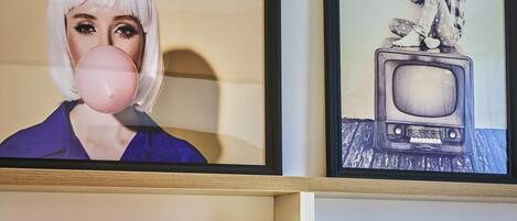 A framed artwork of a person blowing a bubble gum on a wall.