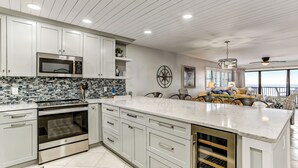 Een moderne keuken met witte kasten, een groot eiland en een achterwand met blauwe en witte tegels.