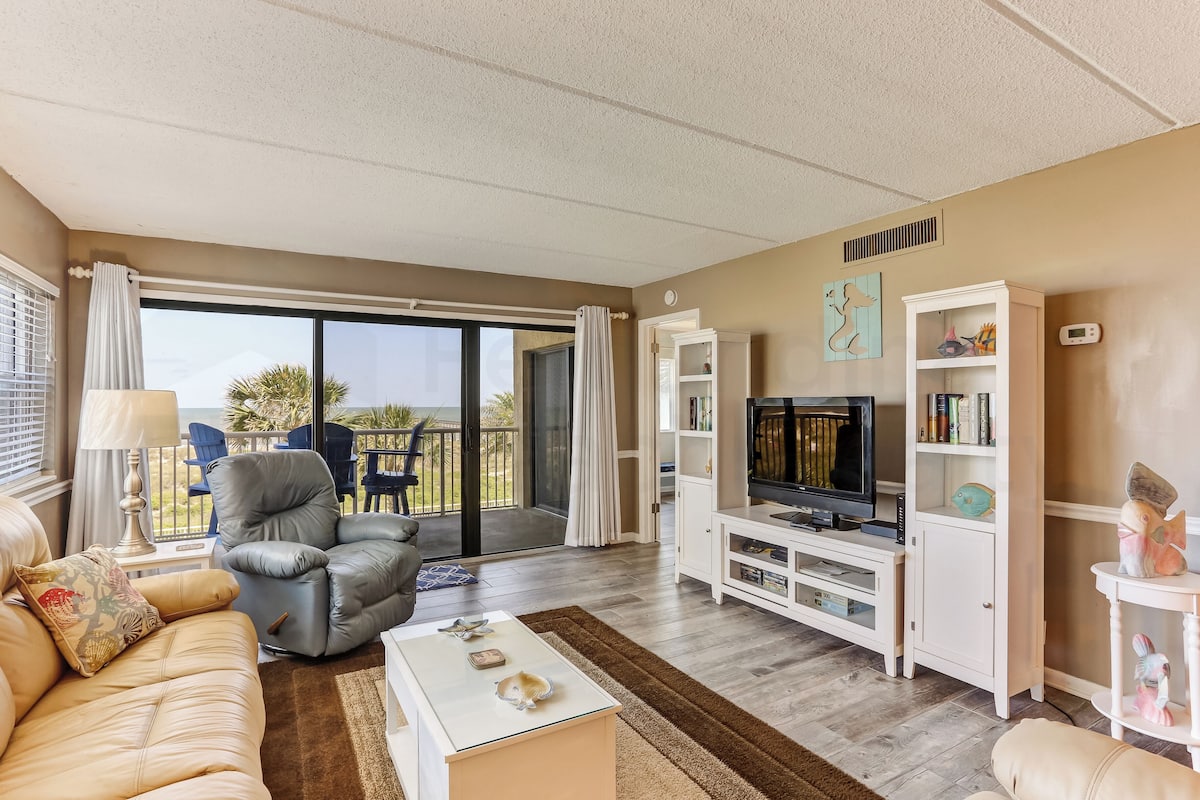 A living room with a sofa, armchair, TV, and entertainment unit.