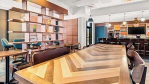A modern bar area with wooden furniture and shelves, a large wooden table, and a bar counter with various bottles.
