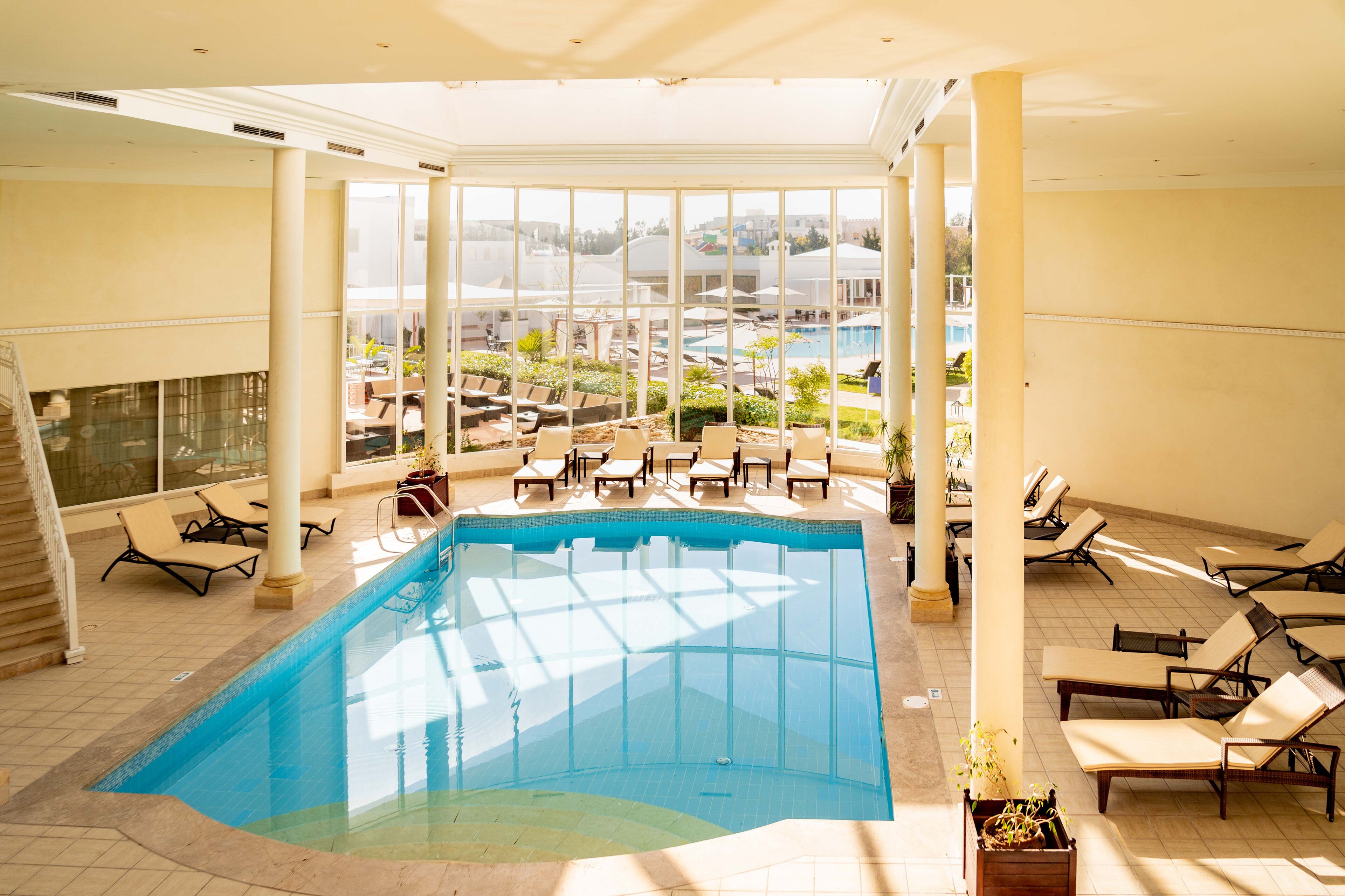 Una piscina interior con sillas de descanso y vistas al exterior.