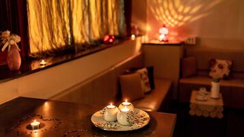 A cozy seating area with a table featuring three candles, a decorative plate, and a small vase.