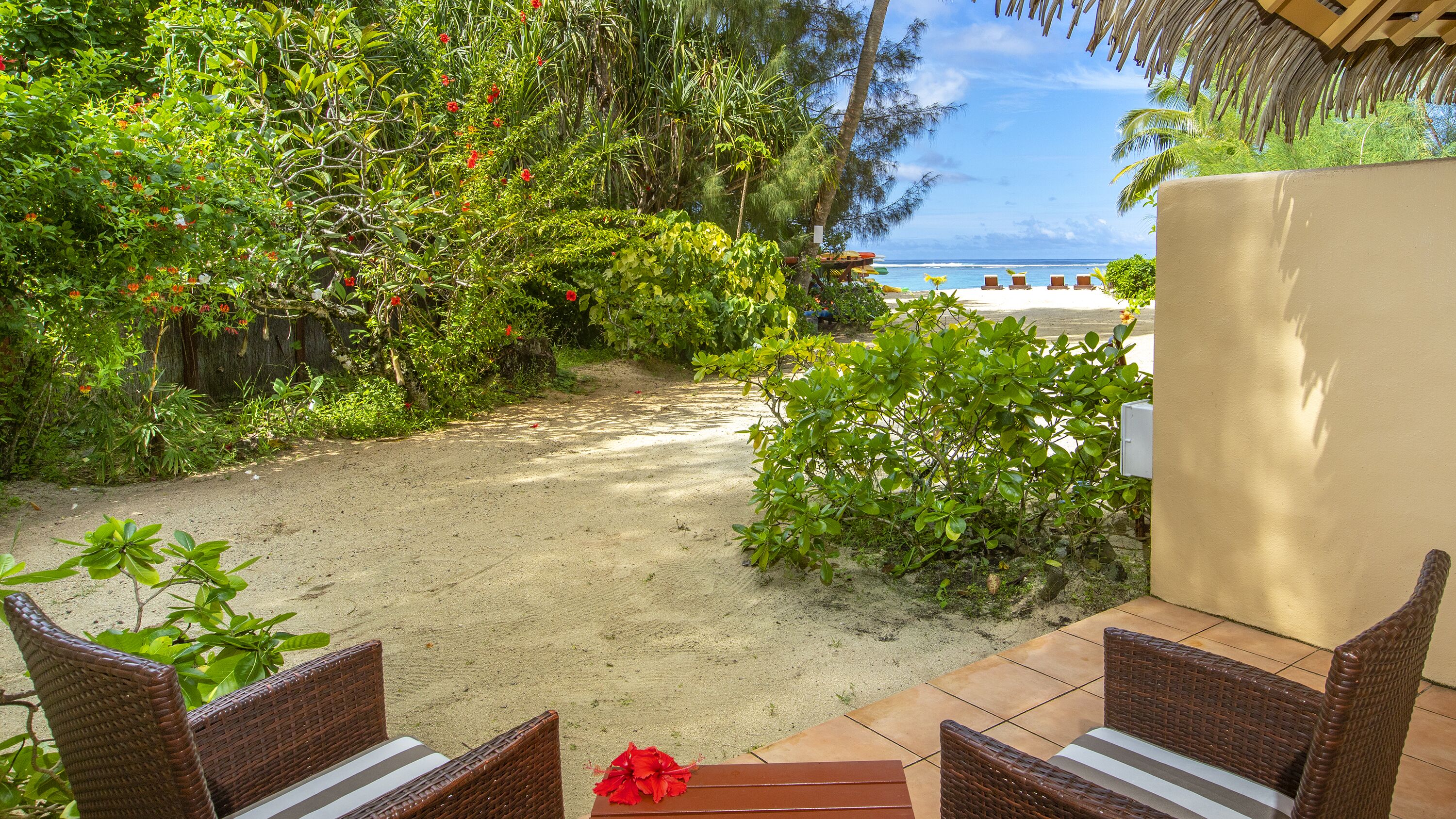 A beachside patio with wicker furniture and a view of the ocean.