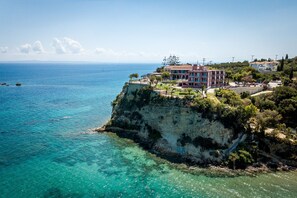 A coastal building with a balcony overlooking the sea, situated on a cliff with clear waters. - Balcony Hotel - Adults Only (Zakynthos)