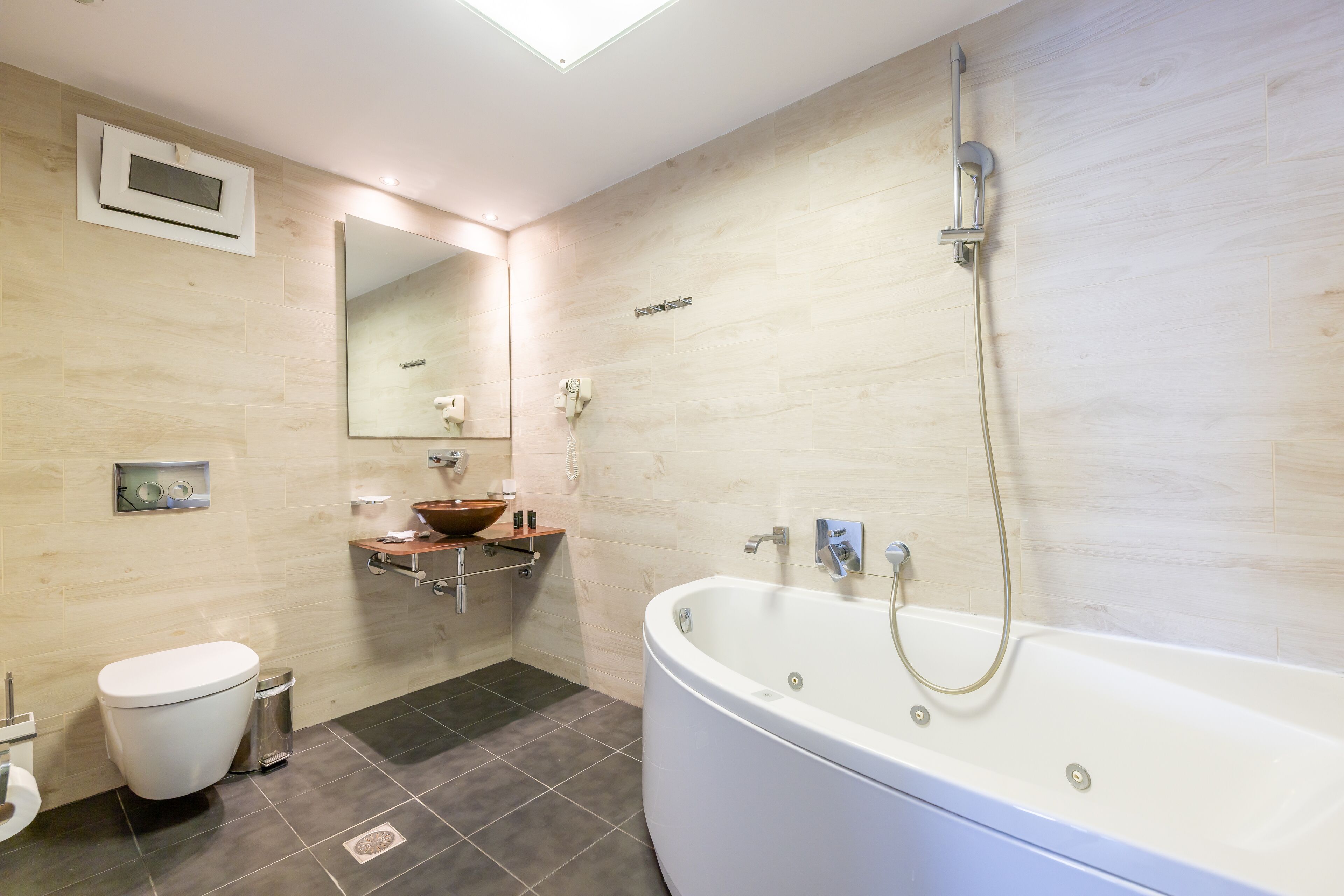 A modern bathroom with a freestanding bathtub, a toilet, a vanity with a mirror, and a showerhead.