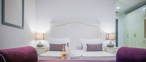 A hotel room with a large bed, two bedside tables, a wardrobe, and a framed picture on the wall.