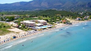 Vista aérea de uma área costeira com praia, área de piscina e edifícios.