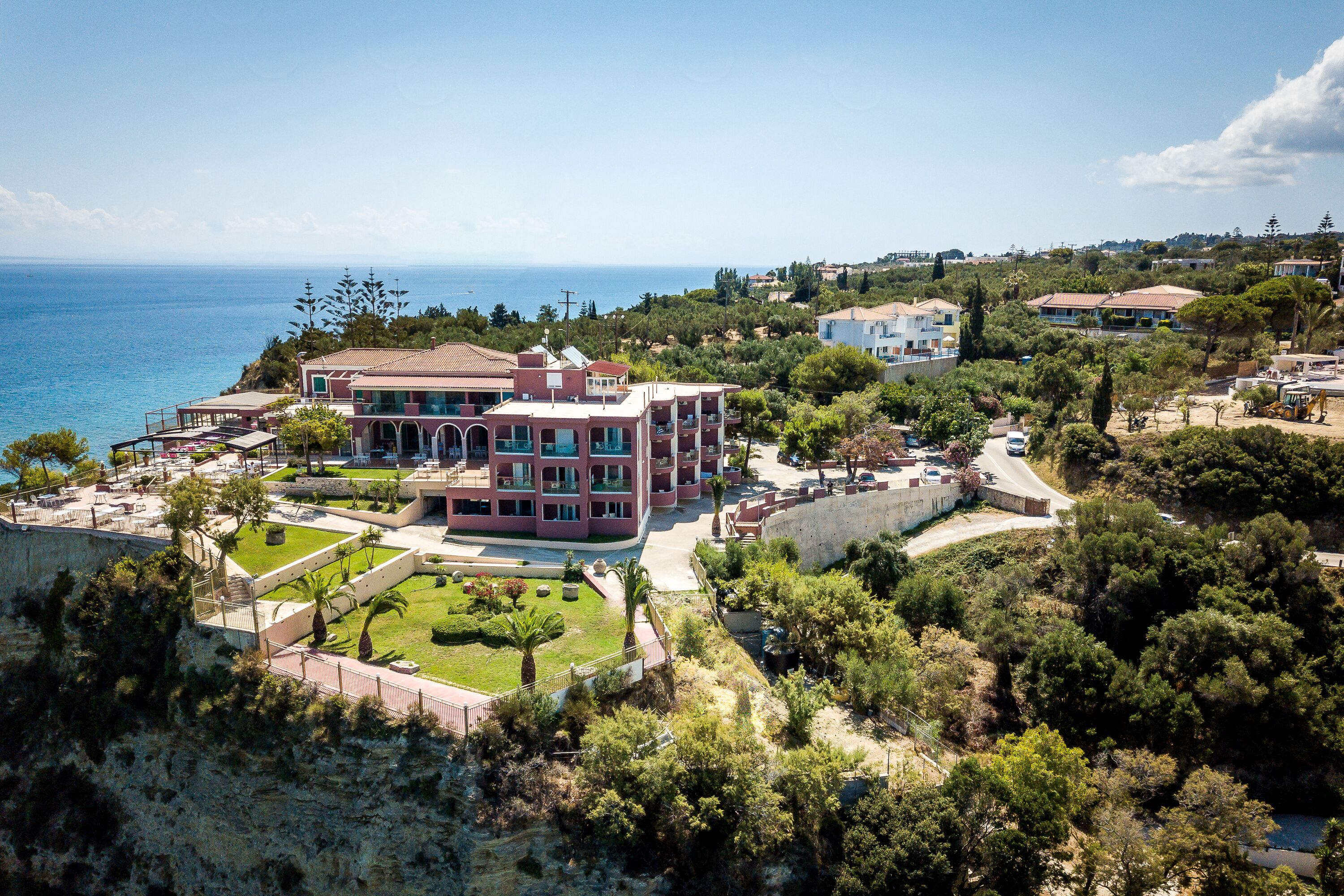 A coastal property with a large building, landscaped gardens, and a view of the sea.