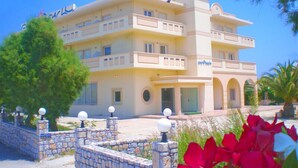 A multi-story hotel with a light yellow facade, balconies, and a stone entrance. - Galini Beach Hotel (Kissamos)