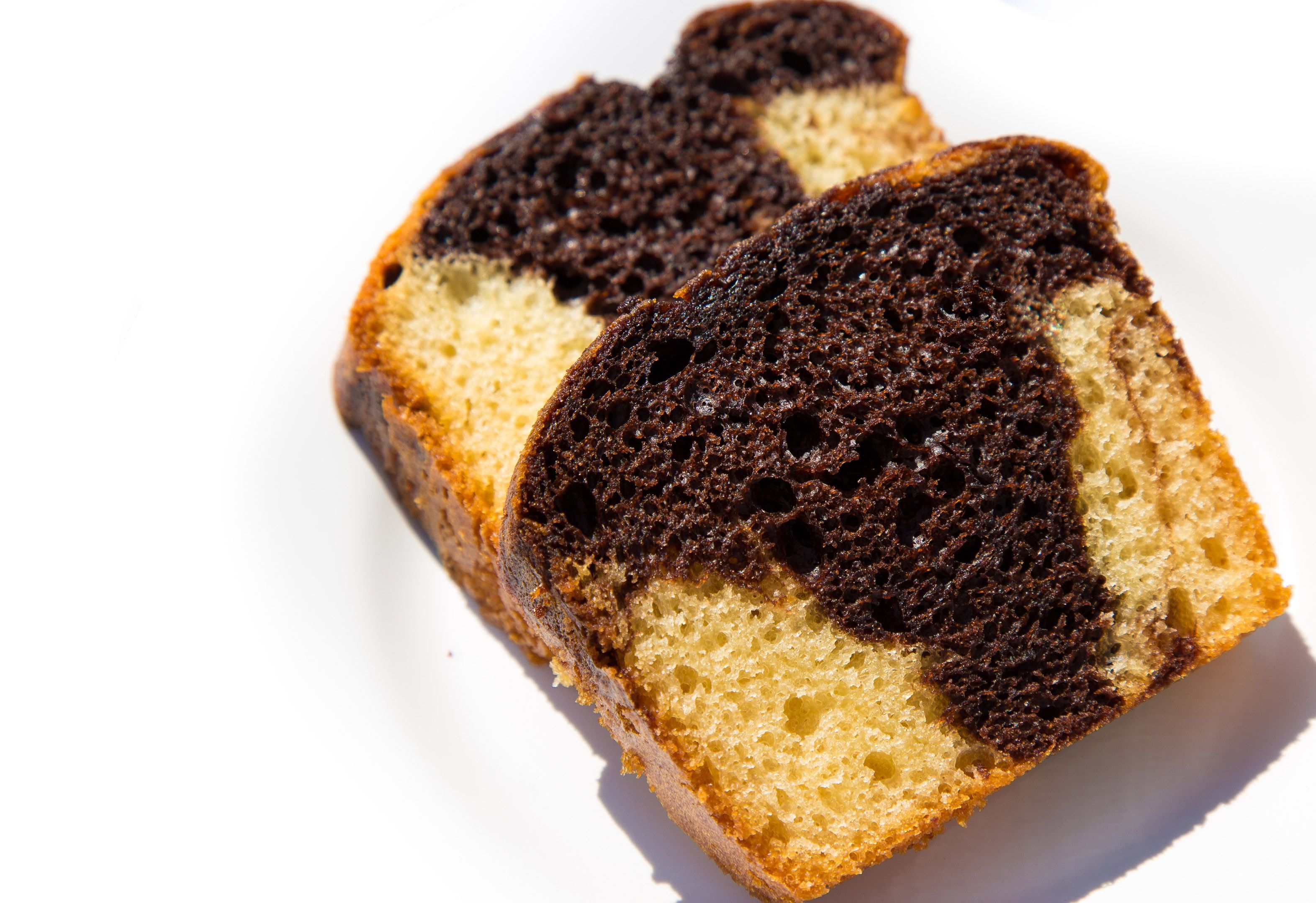 Dos porciones de pastel con cobertura de chocolate oscuro y una base de color amarillo claro.