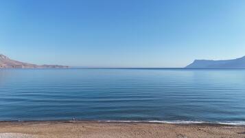 Una spiaggia con acque calme e montagne in lontananza.
