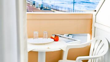 A balcony with a white table, two glasses, and a tomato.