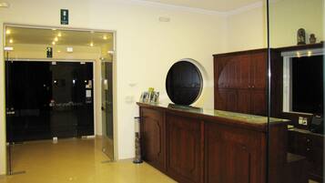 A reception area with a wooden counter, a glass door, and a wall-mounted television.