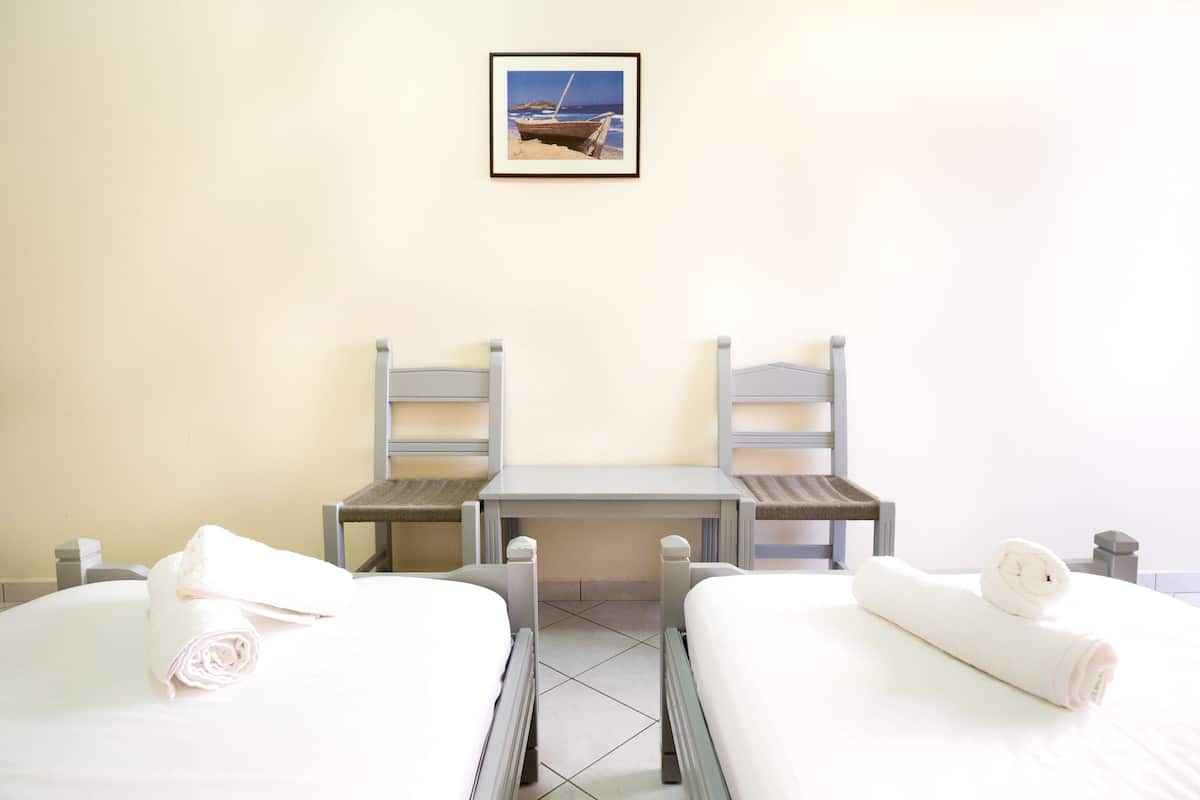 A hotel room with two beds, a small table, and a chair.