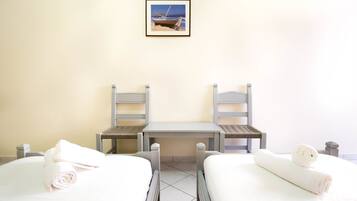 Een hotelkamer met twee bedden, een tafeltje en een stoel.