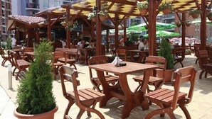 An outdoor café with wooden tables and chairs, potted plants, and a covered seating area. - Rainbow 3 Resort Club (Sunny Beach)