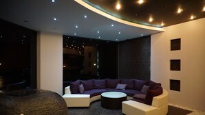 A modern living room with a curved sectional sofa, a round coffee table, and a large decorative vase. - Rainbow 3 Resort Club (Sunny Beach)