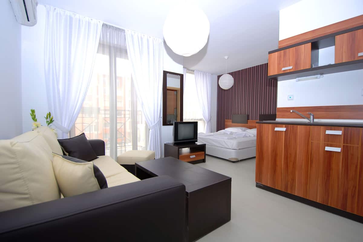 Quarto de hotel moderno com sofá, cama, televisão e um armário de madeira.