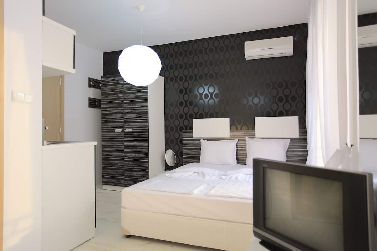 Quarto de hotel moderno com cama, televisão, guarda-roupa e espelho.