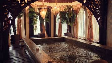Relax by the serene pool surrounded by a wooden deck and ornate arches.