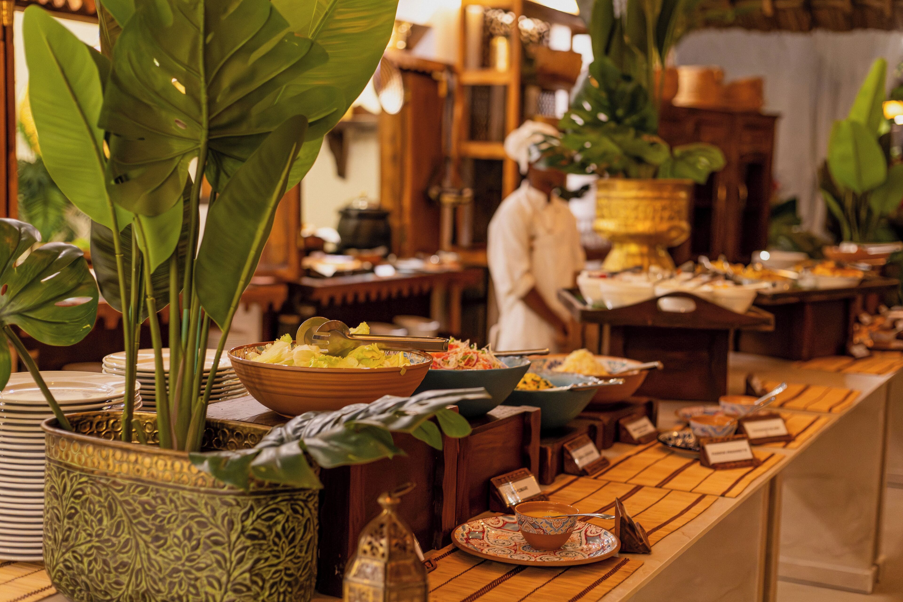 A buffet setup with various dishes and a chef in the background.