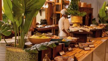 A buffet setup with various dishes and a chef in the background.