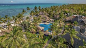 Un complexe hôtelier doté d’une piscine, de palmiers et offrant une vue sur l’océan.