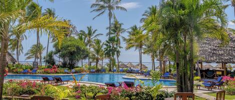 A poolside area with wooden deck, lounge chairs, and a view of the ocean.