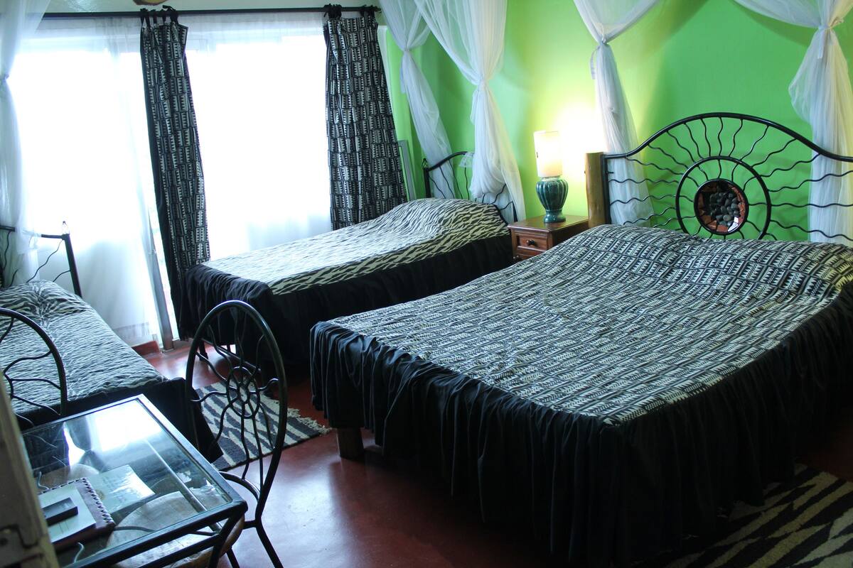 Una habitación con dos camas, una mesita y una silla.