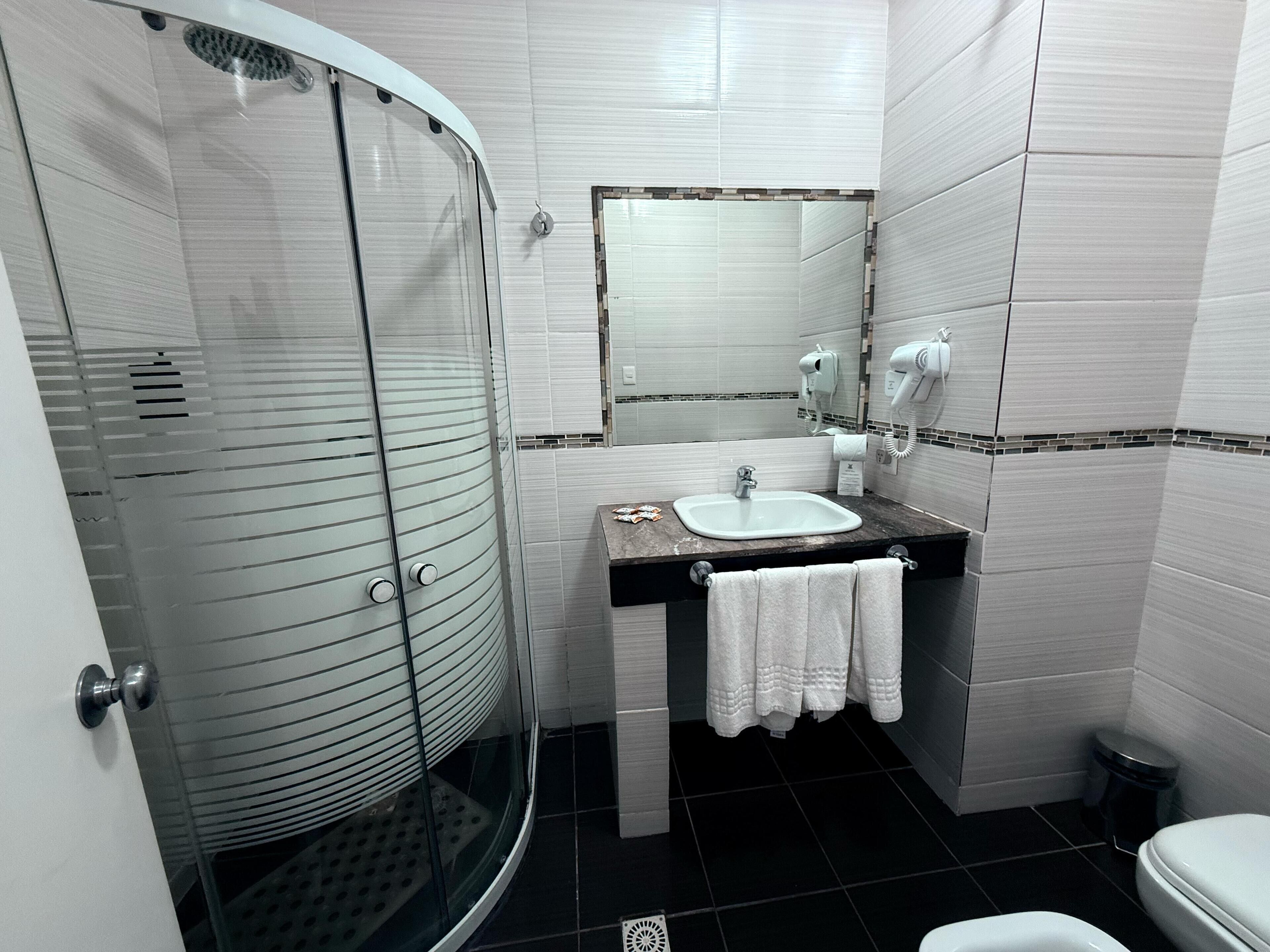 Une salle de bain moderne avec une douche à parois de verre, un lavabo avec une serviette et des toilettes.