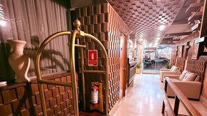 A hotel lobby with a checkered ceiling, a fire extinguisher, a reception desk, and seating area. - Shelton Hotel (Punta del Este)