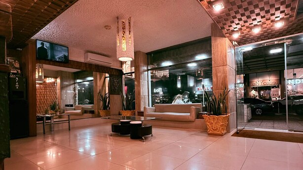 A spacious lobby with a high ceiling, a flat-screen TV mounted on the wall, and a reception desk. - Shelton Hotel (Punta del Este)