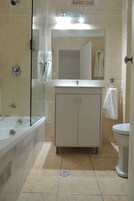 A bathroom with a bathtub, a sink, a toilet, and a glass-enclosed shower area.