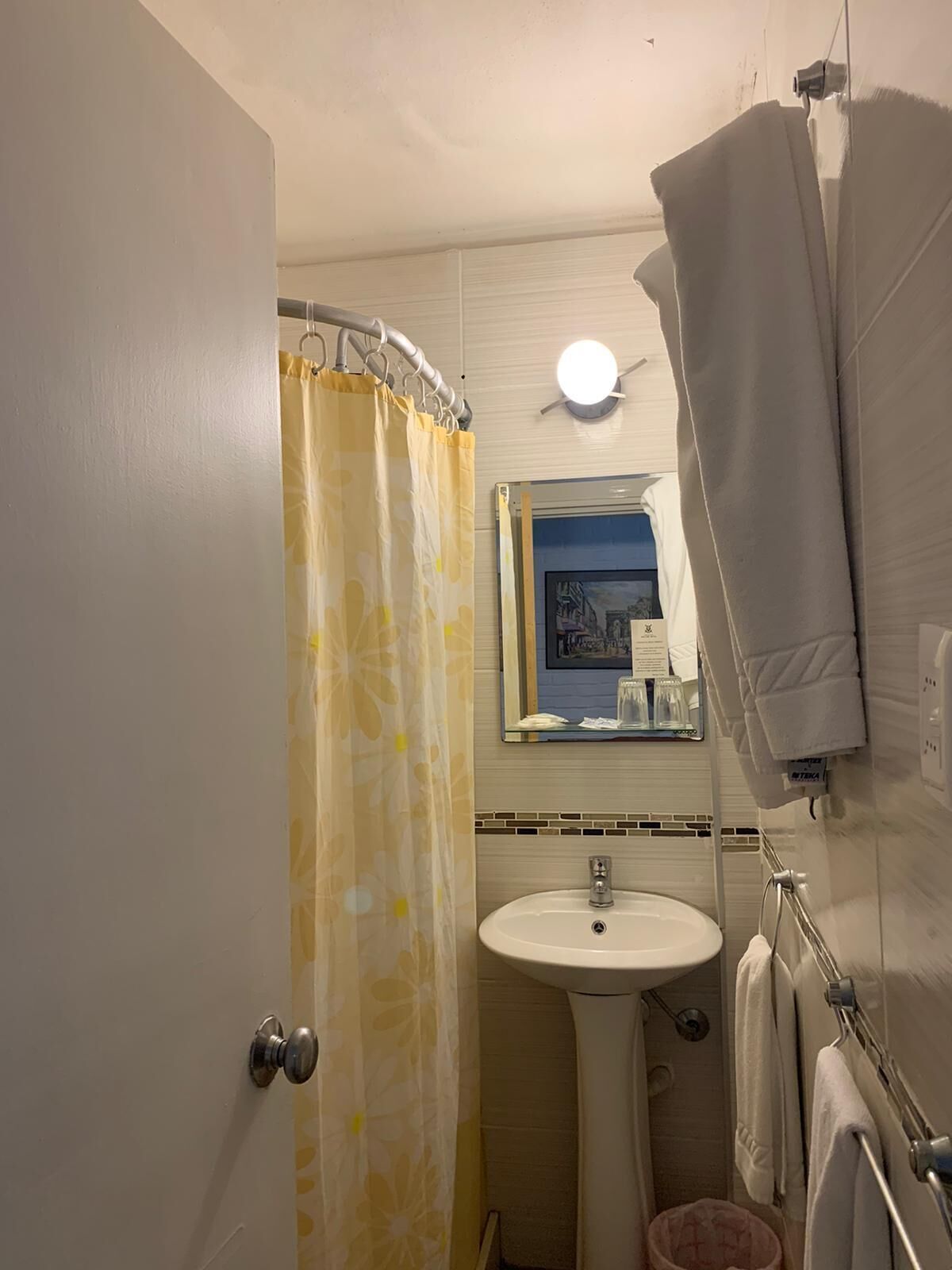 A bathroom with a shower curtain, a sink, a mirror, and a towel rack.