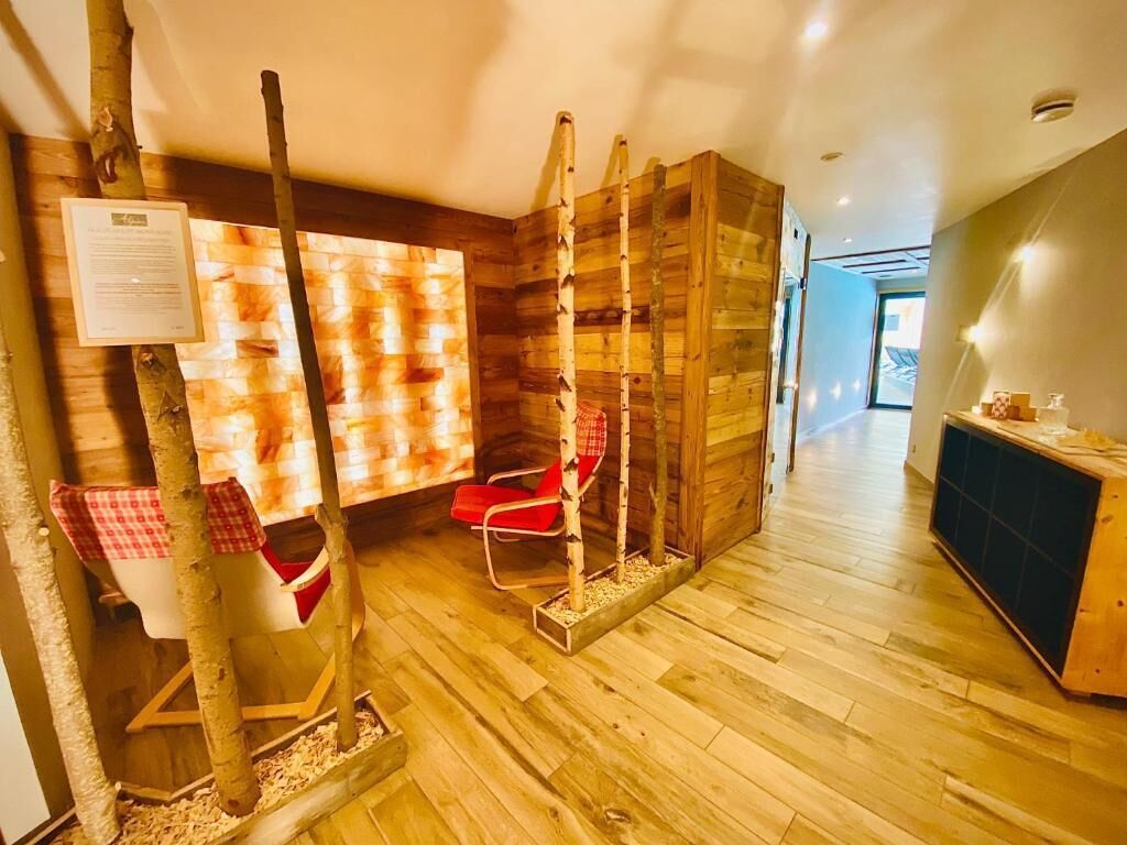 A room with wooden flooring, a red chair, a wooden wall, and a wooden cabinet.
