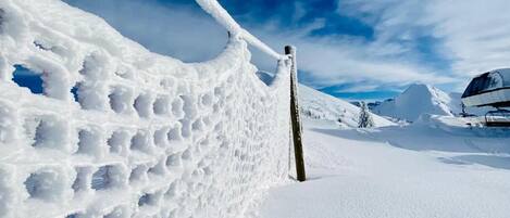 A snow-covered landscape with a snow fence and a clear sky.